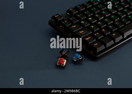 Mechanische RGB-Tastatur für Gamer auf einem Schreibtisch mit seitlichen Schaltern. Stockfoto