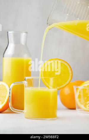 Nahaufnahme eines Glases frisch gepressten Orangensafts, der eingegossen wird Stockfoto