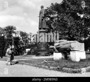 Zwei Frauen sehen Statuen im Muzeon Skulpturenpark, Moskau, Russland. In der Mitte befindet sich eine Statue von Felix Dzerzhinsky (1877-1926), dem polnisch-russischen Agitator und Leiter der Geheimpolizei. Die Statue auf der rechten Seite scheint von Josef Stalin zu sein. Stockfoto