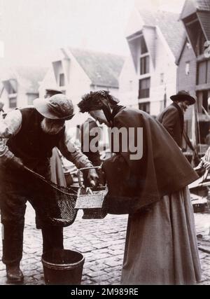 Menschen auf einem Fischmarkt in Stavanger, Norwegen -- eine Frau kauft lebenden Fisch von einem Fischer. Stockfoto