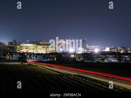 Die Lichter des Autos Streifen nachts zu dichten, hellen Gebäuden am Stadtrand Stockfoto