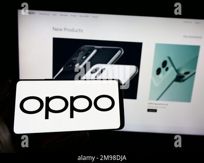 Person, die ein Smartphone mit dem Logo des chinesischen Unterhaltungselektronikunternehmens OPPO auf dem Bildschirm vor der Website hält. Konzentrieren Sie sich auf das Display des Telefons. Stockfoto