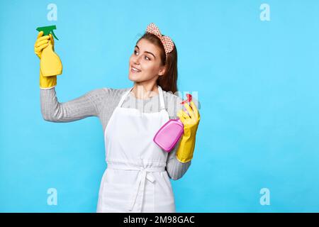 Frau mit Gummihandschuhen wählt zwischen zwei Reinigungsprodukten Stockfoto