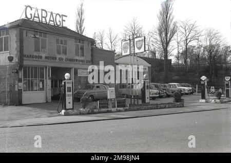 1957, historisch, von der Hargood Motor Co auf der Wilmslow Rd, Didsbury, Manchester, England, Großbritannien. Auf dem Dach des zweistöckigen Gebäudes wird das Wort Garage in großen Großbuchstaben angezeigt, und die Autos des Tages stehen vor dem Autohändler rechts neben dem Bild. Wie die Schilder und die Tankstellen auf dem Vorplatz zeigen, wurden dem Autofahrer dieser Ära verschiedene Kraftstoffmarken wie BP, Shell, Power und National angeboten. Stockfoto