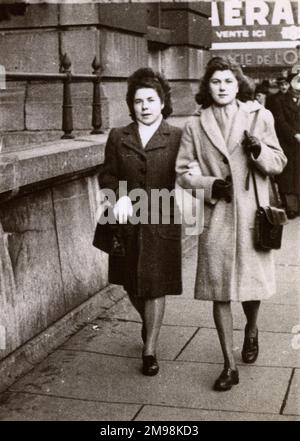 Zwei französische Damen für einen Spaziergang in der Stadt (vielleicht Paris?) Arm in Arm an einem kalten Wintertag. Stockfoto