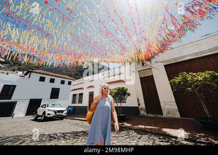 Eine Blondine in einer Sundress mit einem Rucksack geht entlang der Straße der Altstadt von Garachico auf der Insel Teneriffa.Spanien, Kanarische Inseln Stockfoto