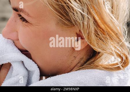 Nahaufnahme des Gesichts einer Frau mit vulkanischem schwarzen Sand am Strand. Stockfoto