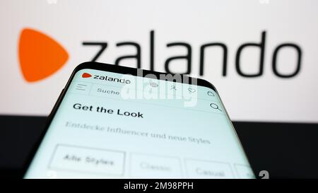Mobiltelefon mit Website des deutschen E-Commerce-Unternehmens Zalando SE auf dem Bildschirm vor dem Firmenlogo. Fokus auf oberer linker Seite des Telefondisplays. Stockfoto
