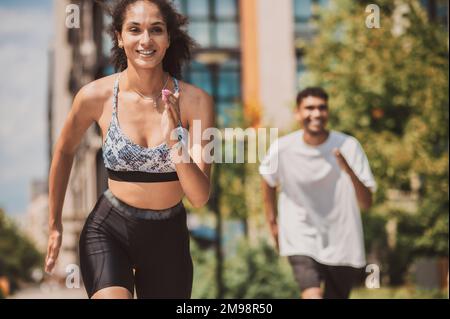 Fröhliche, energetische Sportlerin, die an einem Sportwettbewerb teilnimmt Stockfoto