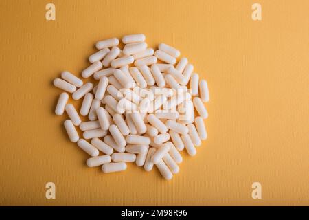 Eine Nahaufnahme weißer Kapseln auf gelbem Hintergrund Stockfoto