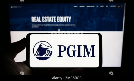 Person, die ein Mobiltelefon mit dem Logo der US-amerikanischen Vermögensverwaltungsgesellschaft PGIM Inc. Auf dem Bildschirm vor der Unternehmenswebseite hält. Konzentrieren Sie sich auf das Display des Telefons. Stockfoto