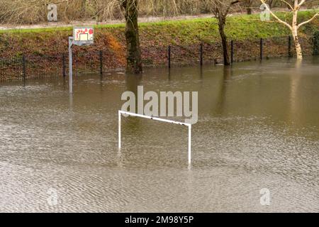 Weiße Torpfosten auf einem Fußballfeld und ein Korb auf einem Basketballfeld unter Wasser aufgrund von Überschwemmungen. Keine Menschen. Stockfoto