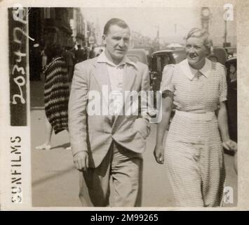 Ein Paar, das im Urlaub an der Front in Weymouth, Dorset, spaziert. Stockfoto