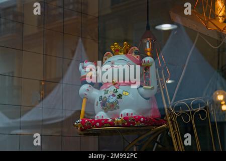 Eine Glückskatze, Maneki-Neko oder Zhaocai Mao in einem chinesischen Schaufenster Stockfoto
