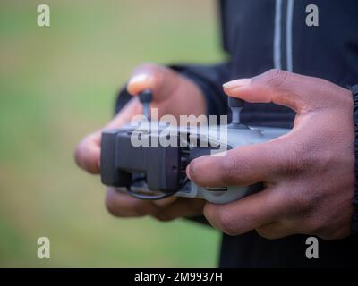 Ein fröhlicher junger Teengaer aus afroamerikanern in Sportbekleidung, der eine Drohne in einem Park fliegt. Stockfoto