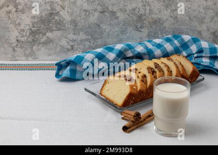 Walnussbrot mit einem Glas Milch auf einem Tisch mit blauer Tischdecke im Hintergrund. Stockfoto