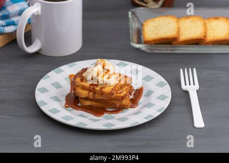 Frühstück mit getoastetem Brot mit cajeta und Banane, begleitet von einer Tasse Kaffee. Stockfoto