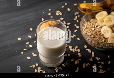 Nähern Sie sich einer Schüssel Haferflocken mit Banane, einem Glas Milch und Keksen, mit Platz zum Kopieren. Stockfoto