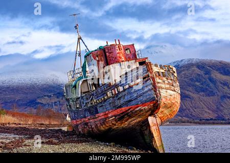 Old Boat of Caol Fort William Schottland Boot am Strand verlassen und Ben Nevis im Winter mit Schnee bedeckt Stockfoto