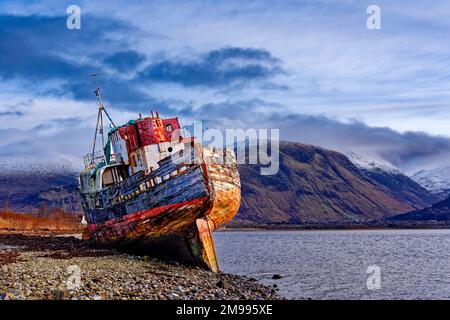 Old Boat of Caol Fort William Schottland Boot verlassen am Strand und Schnee über der Nevis Bergkette Stockfoto
