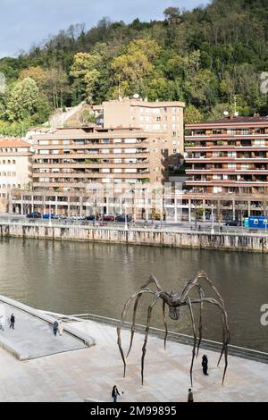 Blick über den Fluss Nervión vom Guggenheim Bilbao, mit Maman by Louise Bourgeois im Vordergrund und Gebäuden und einem Hügel im Stockfoto