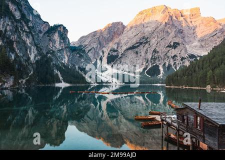 Atemberaubende Aussicht auf den Pragser See (Lago di Prags) mit einigen Holzbooten und wunderschönen Bergen, die sich im Wasser spiegeln. Stockfoto