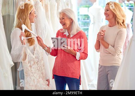 Verkaufsassistentin Mit Mutter Hilft Der Erwachsenen Tochter Bei Der Auswahl Des Hochzeitskleids Im Brautgeschäft Stockfoto