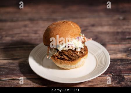 Schweinefleisch-Sandwich mit Krautsalat auf einem Teller Stockfoto