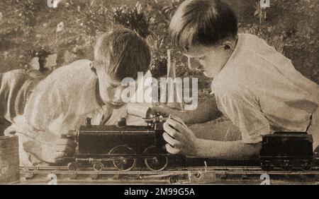 1930- zwei Schuljungen spielen mit ihrer Modelllokomotive. Stockfoto