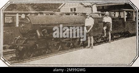 Eine 1930-Grad-Ansicht von zwei Jungen in kurzen Hosen und Sonnenschutzhauben, die neben dem Zug des nördlichen Häuptlings auf der Hythe-Dymchurch Miniatur railway.jpg stehen. Stockfoto