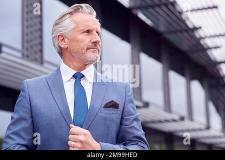 Portrait des ernsthaften Senior Business CEO Chairman, der vor dem modernen Bürogebäude steht Stockfoto