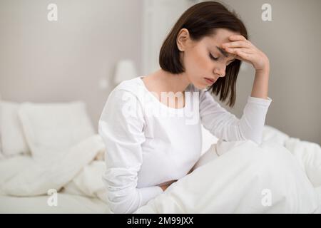 Kranke Frau mit Kopfschmerzen im Bett Stockfoto