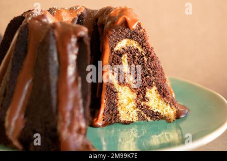 Ein Schokoladen- und Vanille-Marmorkuchen mit einem Milchschokoladenüberzug. Der Kuchen ist geschnitten und plattiert Stockfoto