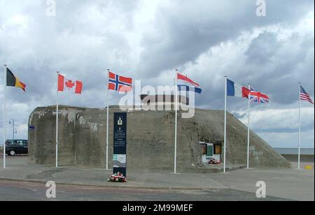 Dieser Bunker am Ufer von Gold Beach hat den Hampshires und Dorsets viel Ärger bereitet, als sie am D-Day um 0730 Uhr an Land kamen. Es wurde schließlich von Sergeant R. E. Palmer mit einer 25 pdr-Selbstfahrpistole auf 300 Yards ausgeschaltet, in einer Aktion, die ihm die Militärmedaille einbrachte. An der Bunkerwand befinden sich Gedenkplakate für die Essex Yeomanry und das 147. Feldrekiment RA. Stockfoto