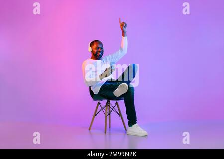 Ein cooler schwarzer Mann, der Musik hört, mit Telefon und Kopfhörern Stockfoto