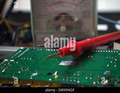 Prüfung elektronischer Geräte oder Fehlersuche mit einem Multimeter. Hintergrund der Elektronikindustrie. Leiterplatte und Ohmmeter. Stockfoto