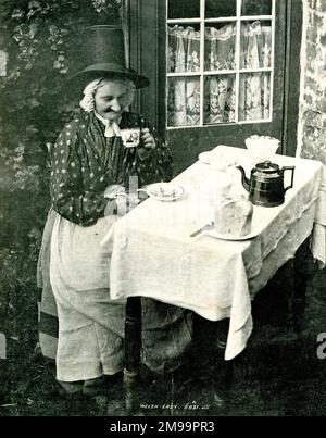Walisische Frau in traditionellem Nationalkostüm, sitzt an einem Tisch und trinkt Tee. Stockfoto