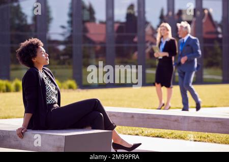 Geschäftsreisende entspannen sich vor dem modernen Bürogebäude Stockfoto