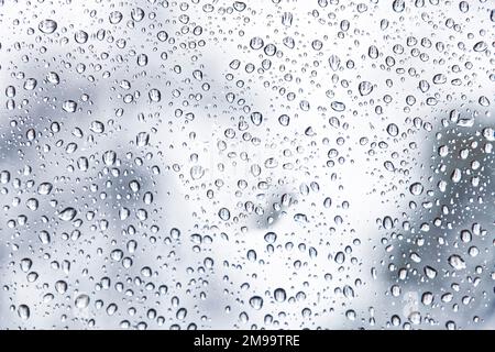 An einem Regentag fällt Regen auf das Glas des Fensters Stockfoto