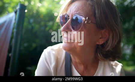 Eine ältere Frau trägt draußen eine große Sonnenbrille Stockfoto