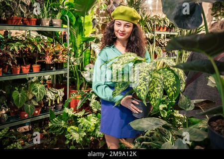 Junge Frau, die heimische grüne Pflanzen in einem Laden auswählt Stockfoto