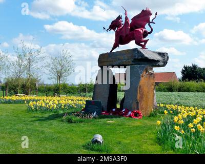 Diese schöne Gedenkstätte in Belgien richtet sich nicht nur an die 38. Walisische Division, sondern an alle walisischen Truppen, die im Ypern-Hauptquartier gekämpft haben. Sie ähnelt dem Drachen in Mametz an der Somme. Hier ist es von Narzissen umgeben und steht in einem kleinen Bereich neben der Straße, wo ein Sitz auf diejenigen wartet, die sitzen und nachdenken möchten. Die in der Nähe ansässigen belgischen Einwohner, die eine große Rolle bei der Anstiftung, Finanzierung und Ermöglichung der Gedenkfeier gespielt haben, heben die walisische Flagge und läuten den letzten Poston am ersten Montag jedes Monats. Stockfoto