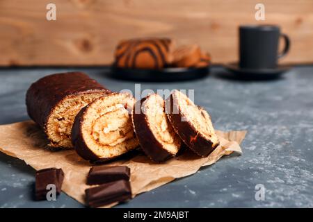 Backpapier mit köstlichen Kuchenrollen und Schokolade auf grauem Tisch Stockfoto