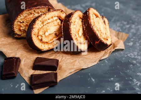 Backpapier mit köstlichen Kuchenrollen und Schokolade auf grauem Tisch Stockfoto