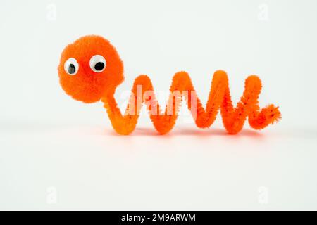 Gänsehaut Pom Pfeifenreiniger Wriggly Wurm lustige Figur Kinderspielzeug Hand isoliert auf weißem Hintergrund Stockfoto