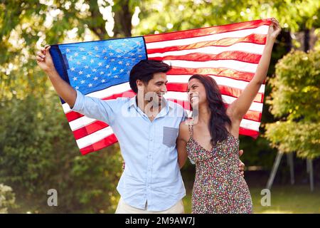Portrait des Patriotic American Ehepaars Holding USA Stars and Stripes Flag Outdoors in Garden Stockfoto
