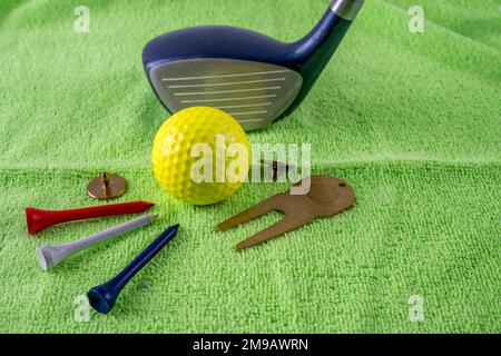 Unverzichtbare Ausrüstung für eine Runde Golfschläger Marker T-Shirts und Reparaturwerkzeug auf einer künstlichen grünen Oberfläche Stockfoto