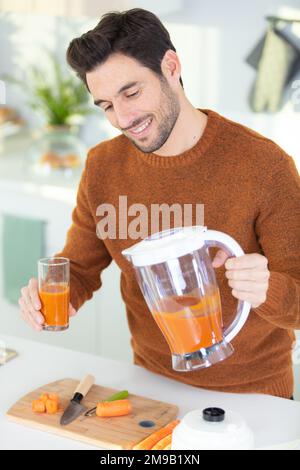 Junger bärtiger Mann trinkt frisch gepressten Natursaft Stockfoto