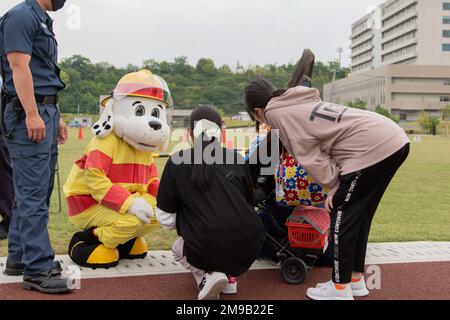 Sparky, das offizielle Maskottchen der National Fire Protection Association (NFPA), begrüßt ein Kind beim Owl Park Inclusive Community Relations Event im Atagoyama Fukuro Park, auch bekannt als Atago Owl Park, in Iwakuni, Japan, am 15. Mai 2022. Die Veranstaltung bot Freiwilligen die Gelegenheit, sich mit der örtlichen Gemeinschaft zu verbinden und eine sichere Umgebung für Kinder mit Behinderungen zu schaffen, um einen Tag im Park zu genießen. Stockfoto