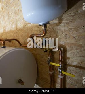 Sanitär-Warmwassertank mit Ausgleichbehälter an neu installierter Zentralheizung Stockfoto